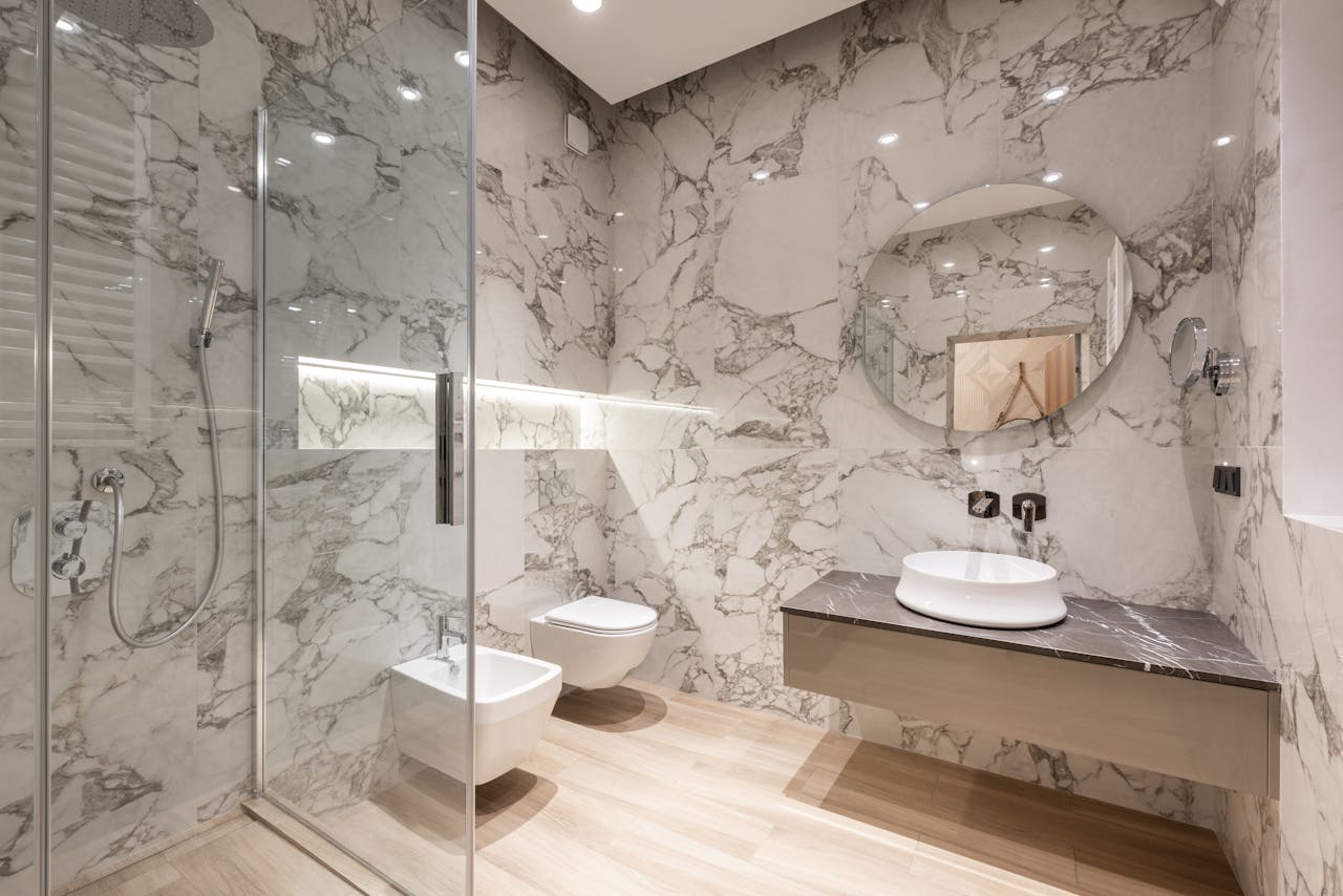 Elegant marble bathroom featuring a round mirror and stylish fixtures for contemporary living.